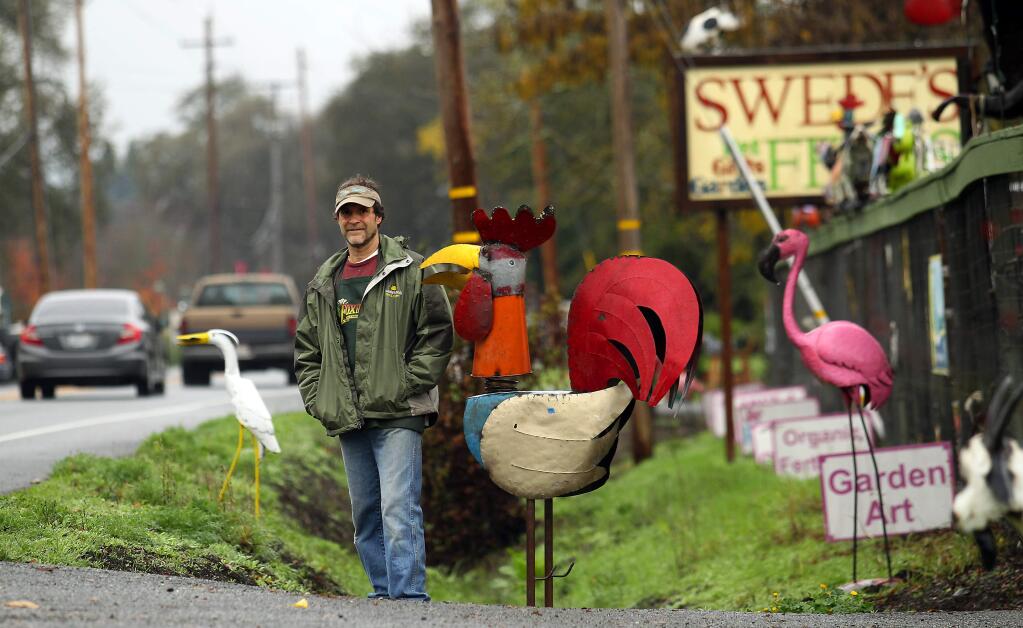 Swede's Feeds co-owner Mike Scheffer stands in front of his Hwy 12 store in Kenwood where he displays metal sculptures he claims are necessary for the viability of his store. (Photo by John Burgess/The Press Democrat).