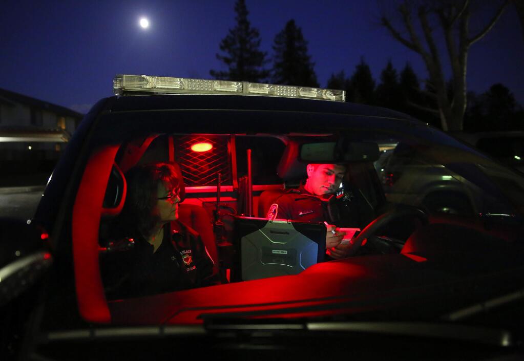 Law enforcement chaplain Lauri McFadden, left, observes while Santa Rosa Police Officer Aaron Gonzales speaks to a restraining order violation suspect on the phone during a ride-along in Santa Rosa, on Wednesday, Dec. 23, 2015. (Christopher Chung / The Press Democrat)