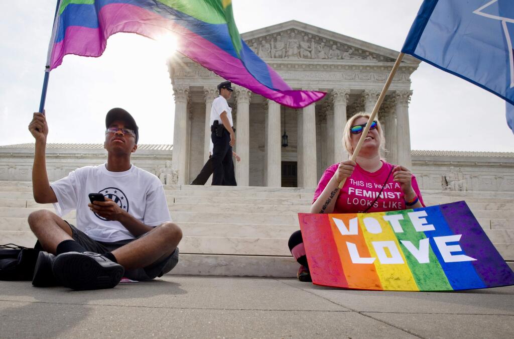 Carlos McKnight, 17, of Washington, left, and Katherine Nicole Struck, 25, of Frederick, Md., hold flags in support of gay marriage as security walks behind outside of the Supreme Court in Washington, Friday June 26, 2015. (AP Photo/Jacquelyn Martin)