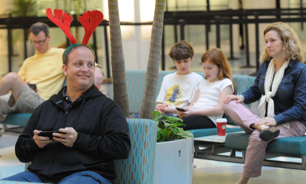 In this Tuesday, Dec. 23, 2014 photo, Greg Hough waits for relatives to arrive from India at the Jacksonville International Airport in Jacksonville, Fla. Christmas Eve is shaping up to be windy, wet and warm instead of white across much of the country, creating headaches for some travelers, especially in the Great Lakes and the Northeast. (AP Photo/The Florida Times-Union, Bob Mack)