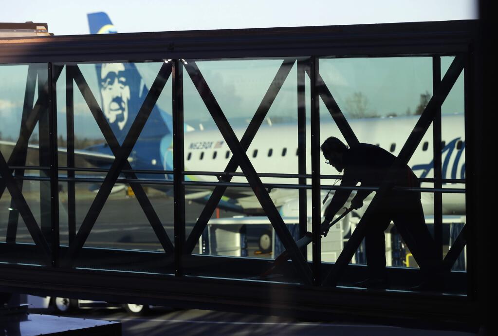 FILE- In this March 4, 2019, file photo a worker cleans a jet bridge before passengers boarded an Alaska Airlines flight to Portland, Ore., at Paine Field in Everett, Wash. U.S. employers are expected to have delivered a solid month of job growth in April, buoyed by a resilient economy that has confounded concerns that 2019 would begin with a slowdown. Another decent hiring gain would highlight the economy's steady health just months after many analysts had expressed fear that growth was poised to weaken and a recession might soon occur. (AP Photo/Ted S. Warren, File)