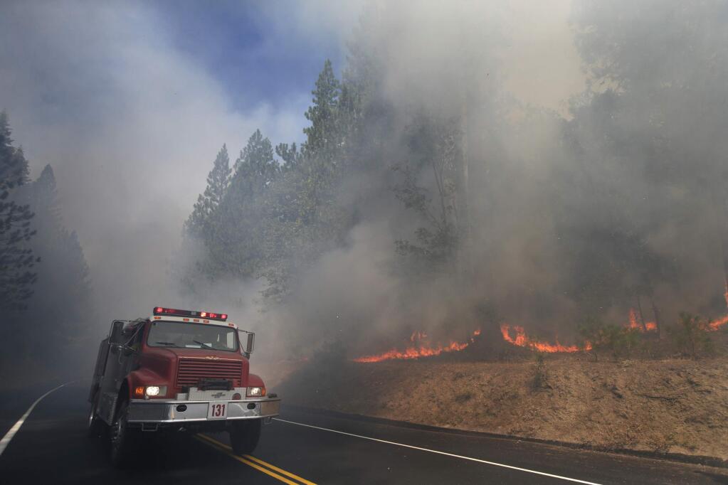 FILE - In this Aug. 26, 2013 file photo, a fire truck drives past burning trees as firefighters continue to battle the Rim Fire near Yosemite National Park, Calif. The California Department of Forestry and Fire Protection says a firefighter has been killed while battling a wildfire near Yosemite National Park. Officials say Heavy Fire Equipment Operator Braden Varney was killed Saturday, July 14, 2018, morning while battling the Ferguson Fire. The fire broke out around 10:30 p.m. Friday night in Mariposa County, near the west end of Yosemite National Park and the Sierra National Forest. (AP Photo/Jae C. Hong, File)