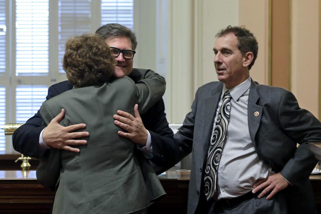 FILE - In this April 30, 2015 file photo, state Sen. Bob Hertzberg, D-Van Nuys, center, gives Sen. Lois Wolk, D-Davis, a hug as Sen. Bob Wieckowski, D-Fremont, looks on at the Capitol in Sacramento, Calif. Hertzberg has been told to stop hugging people after a sexual misconduct investigation concluded his behavior made multiple colleagues uncomfortable. Hertzberg was formally reprimanded Tuesday, March 6, 2018, by the Senate Rules Committee. The Los Angeles-area says he will respect the request not to hug people. (AP Photo/Rich Pedroncelli, File)