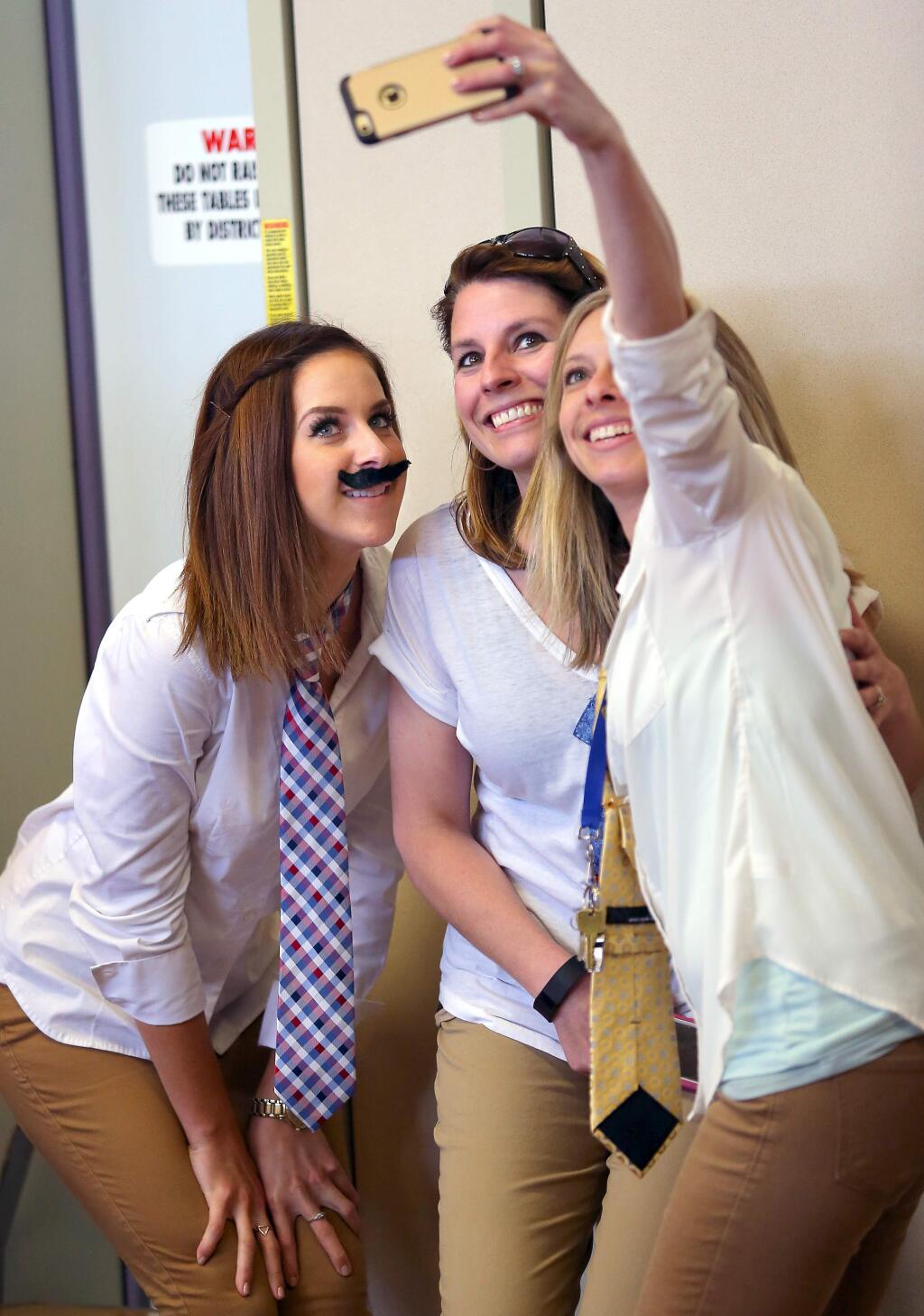 Teachers Katrina Kutz, left, Molly Rhodes, and Amy Nouguier take a picture of themselves dressed as retiring kindergarten teacher Eric Ord, during an assembly in his honor at Whited Elementary School, in Santa Rosa on Friday, April 24, 2015. (Christopher Chung/ The Press Democrat)