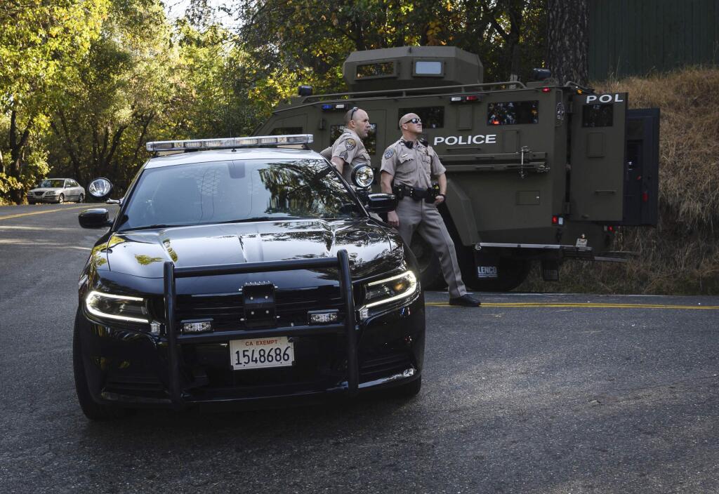 California Highway Patrol officers block off a road where El Dorado County sheriff's deputy Brian Ishmael was killed responding to an early morning call, as an armored vehicle passes by in Somerset, Calif., Wednesday, Oct. 23, 2019. Ishmael was shot to death Wednesday while responding to a call in the rural Sierra Nevada foothills, officials said. The El Dorado County Sheriff's Office said Deputy Brian Ishmael was fatally shot in the community of Somerset and that a ride-along passenger with him was also shot and injured. (Daniel Kim/The Sacramento Bee via AP)