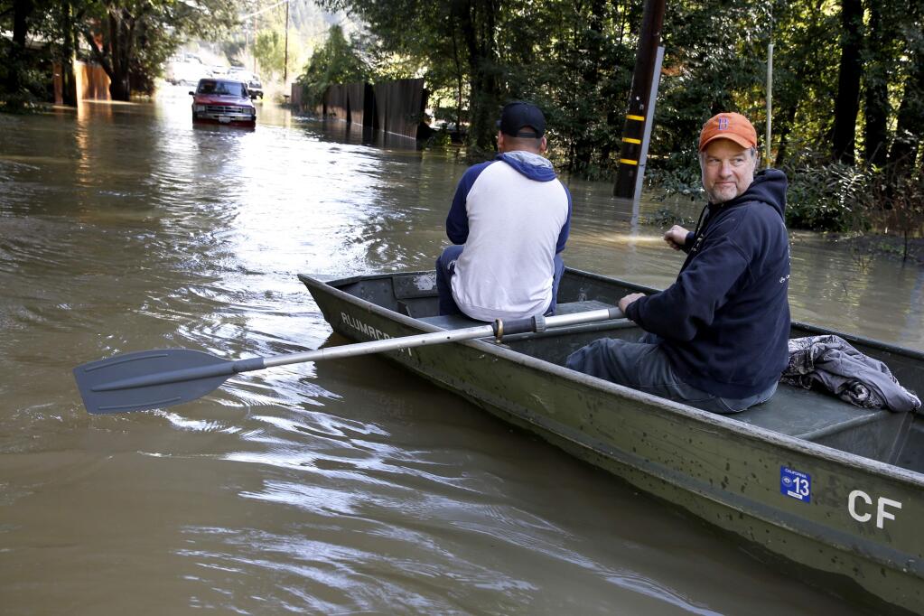 Bruce MacDonell uses his boat to rescue motorist Renaldo Carrasco after his car became stuck in flood waters on Neeley Rd on Friday, February 10, 2017 in Guerneville, California . (BETH SCHLANKER/The Press Democrat)