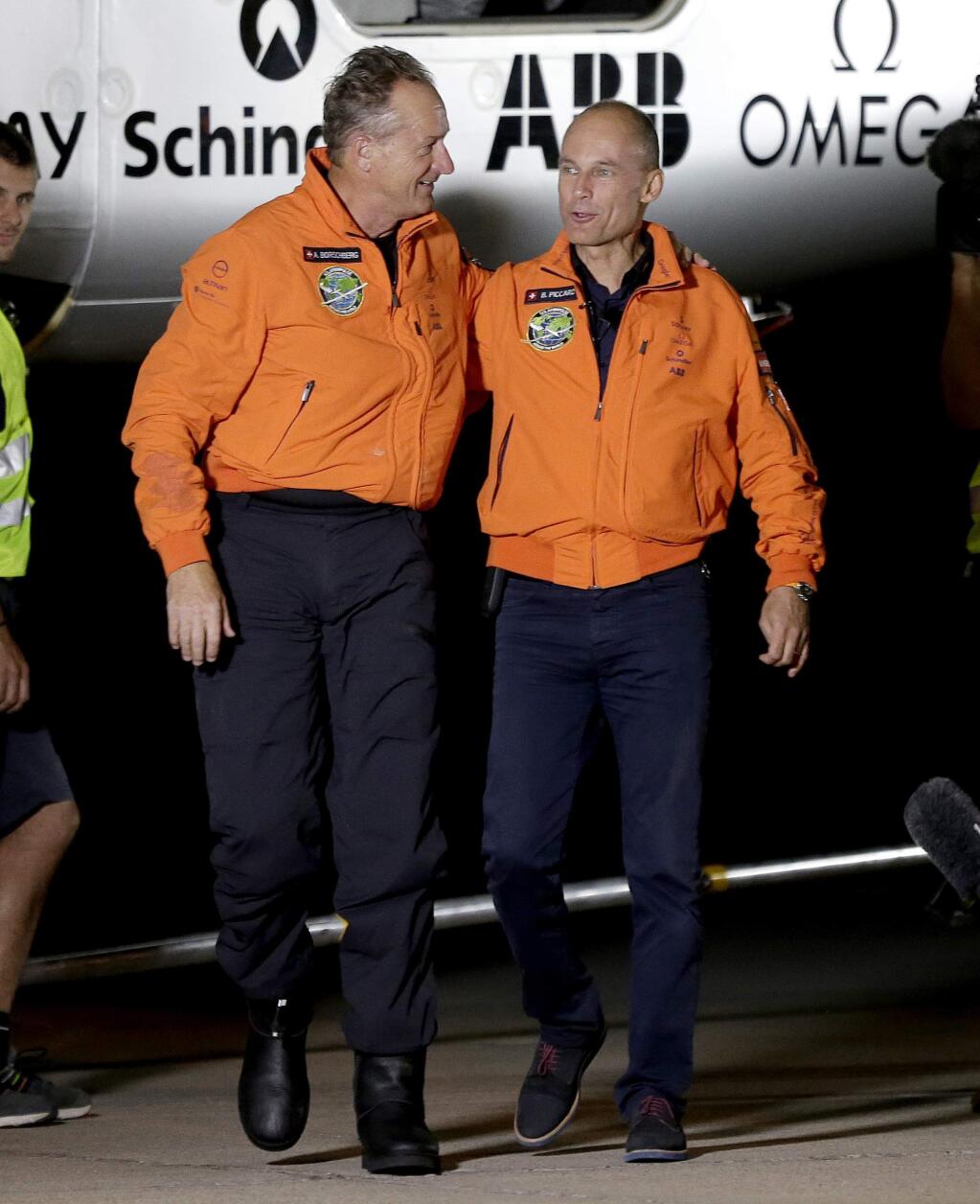 Pilot Andre Borschberg, left, and pilot Bertrand Piccar walk together after Borschberg exited the cockpit of the Swiss-made Solar Impulse 2 plane, Monday, May 2, 2016, in Goodyear, Ariz. The plane left early Monday from California for a 16-hour trip to Phoenix to resume its journey around the world using only energy from the sun. (AP Photo/Matt York)