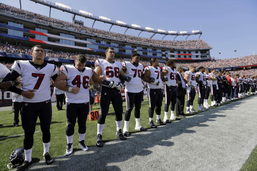Members of the Houston Texans team stand with arms locked during the national anthem before an NFL football game against the New England Patriots, Sunday, Sept. 24, 2017, in Foxborough, Mass. (AP Photo/Steven Senne)