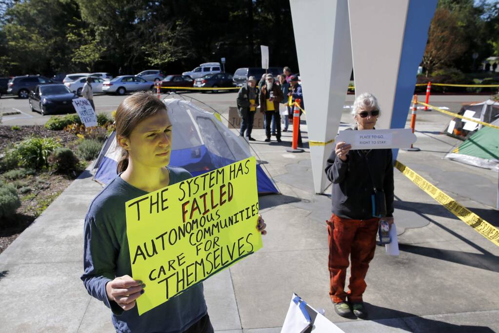 Adrien Shader and Annette Pierson hold signs in support of members of the homeless community outside the Board of Supervisors Chambers on Tuesday, April 17, 2018 in Santa Rosa, California . (BETH SCHLANKER/The Press Democrat)