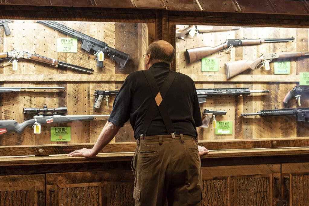 FILE - In this April 25, 2019, file photo, a man looks at cases of firearms in the halls of the Indianapolis Convention Center where the National Rifle Association will be holding its 148th annual meeting in Indianapolis. The number of background checks conducted by federal authorities is on pace to break a record by the end of this year. (AP Photo/Lisa Marie Pane, File)