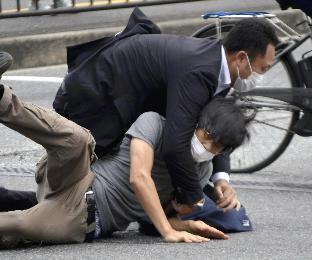 FILE - Tetsuya Yamagami, bottom, is detained near the site of gunshots in Nara Prefecture, western Japan, on July 8, 2022. Japanese prosecutors formally charged the suspect in the assassination of former Prime Minister Shinzo Abe with murder, Japan's NHK public television reported Friday, Jan. 13, 2023. (Katsuhiko Hirano/The Yomiuri Shimbun via AP, File)