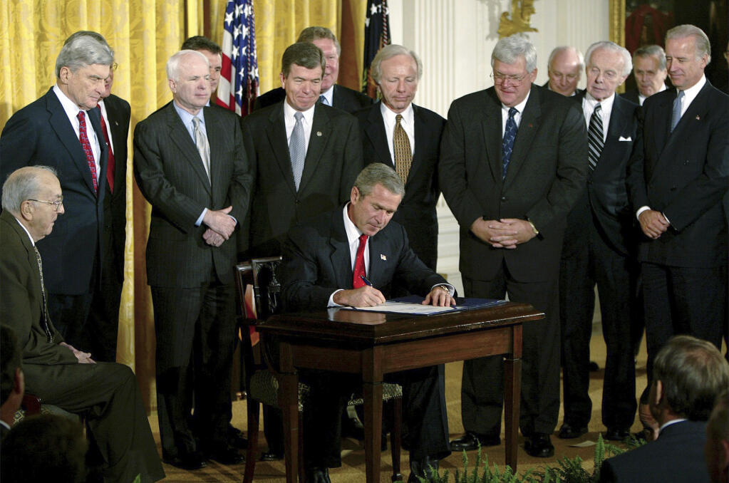 FILE - President George W. Bush signs a resolution authorizing the use of force against Iraq, Oct. 16, 2002, in the East Room of the White House. Left to right, Sen. Jesse Helms, R-N.C., Sen. John Warner, R-Va., Sen. John McCain, R-Ariz., Rep. Roy Blunt, R-Mo., Sen. Joseph Lieberman, D-Conn., Speaker the House Dennis Hastert, R-Ill., Rep. Tom Lantos, D-Calif., Sen. Joseph Biden, D-Del. (AP Photo/Ron Edmonds, File)