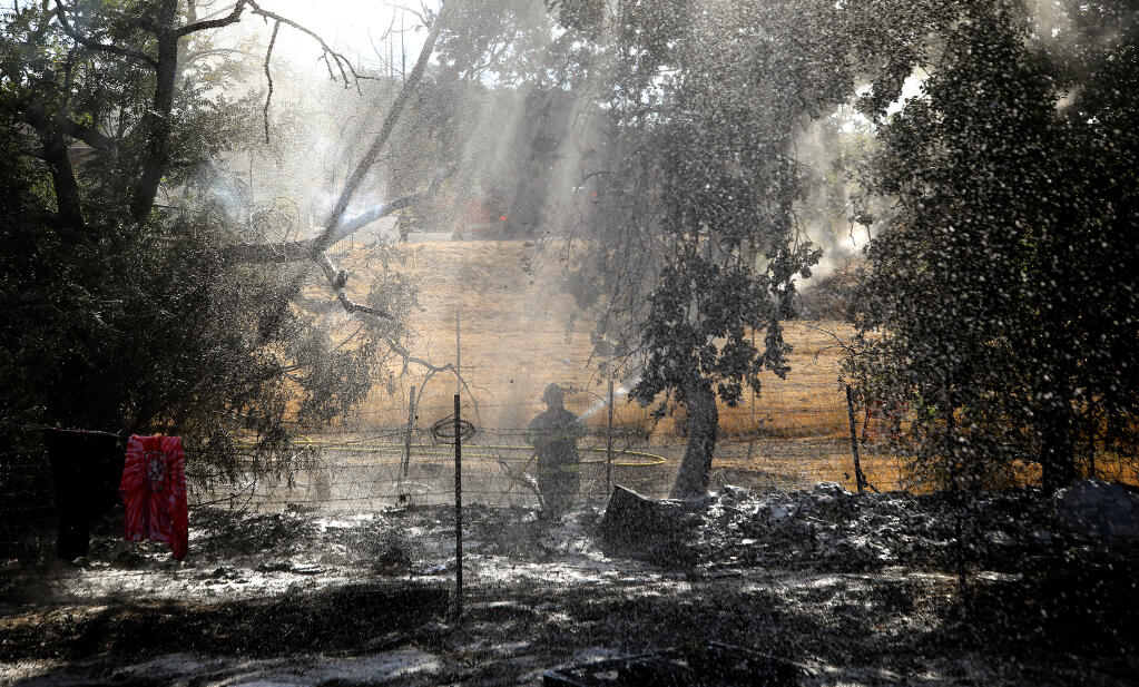 Santa Rosa and Sonoma County Fire District firefighters use water and foam to control a 1/4 acre vegetation fire Thursday, July 28, 2022  that started in a homeless encampment just on the edge of the Hilton Garden Inn, closed since the 2017 Tubbs Fire damaged sections of the resort in Santa Rosa's Fountaingrove area. (Kent Porter / The Press Democrat) 2022