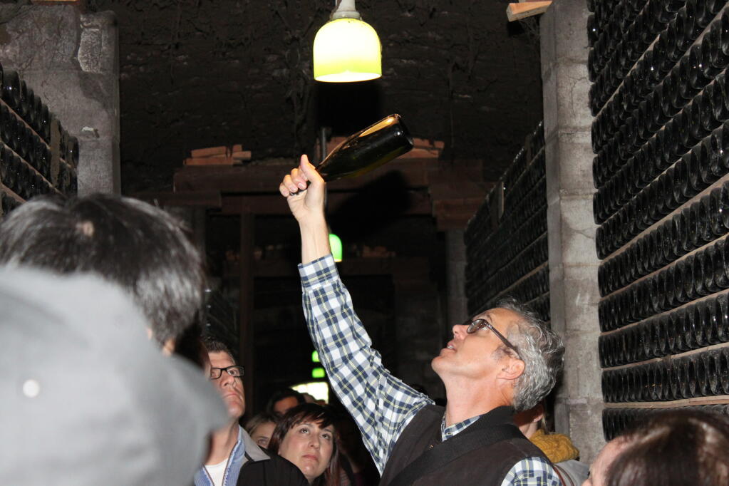 Schramsberg Vineyards proprietor Hugh Davies lifts a bottle aging in the caves for the tour group to see this stage of production for sparkling wine. (Schramsberg Vineyards)