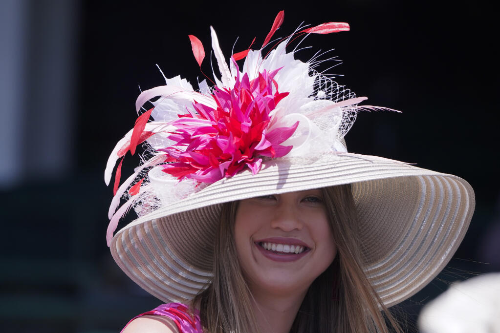 A woman watches a race before the 147th running of the Kentucky Derby at Churchill Downs, Saturday, May 1, 2021, in Louisville, Ky. (AP Photo/Michael Conroy)