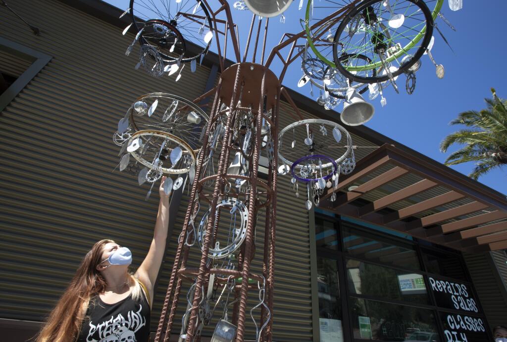 Leila Whitney helps install a new sculpture Aug. 5 in front of Operation Bicycle, a bike-repair program run by Teen Services.  (Photo by Robbi Pengelly/Index-Tribune)