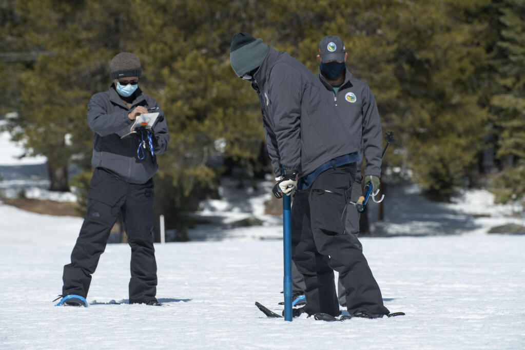 Assisted by Ramesh Gautam, left and Anthony Burdock right, Sean de Guzman, chief of snow surveys for the California Department of Water Resources, checks the depth of the snowpack during the second snow survey of the season at Phillips Station near Echo Summit, Calif., Tuesday, March 2, 2021. The survey found the snowpack at 56 inches deep with a water content of 21 inches. (AP Photo/Randall Benton)