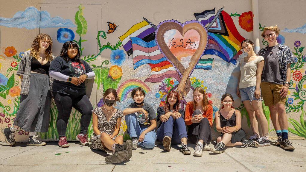 Members of the Healdsburg High School Gender and Sexualities Alliance stand next to the mural they painted this spring. Club president Molly Miller, from left, Plagg Calvo, Sofia Nordvedt, Chris Perez, Bree Guiterrez, Katy Conrad, Stephanie Hensley, Bella Lynch and Liam O’Gorman.(John Burgess / The Press Democrat)