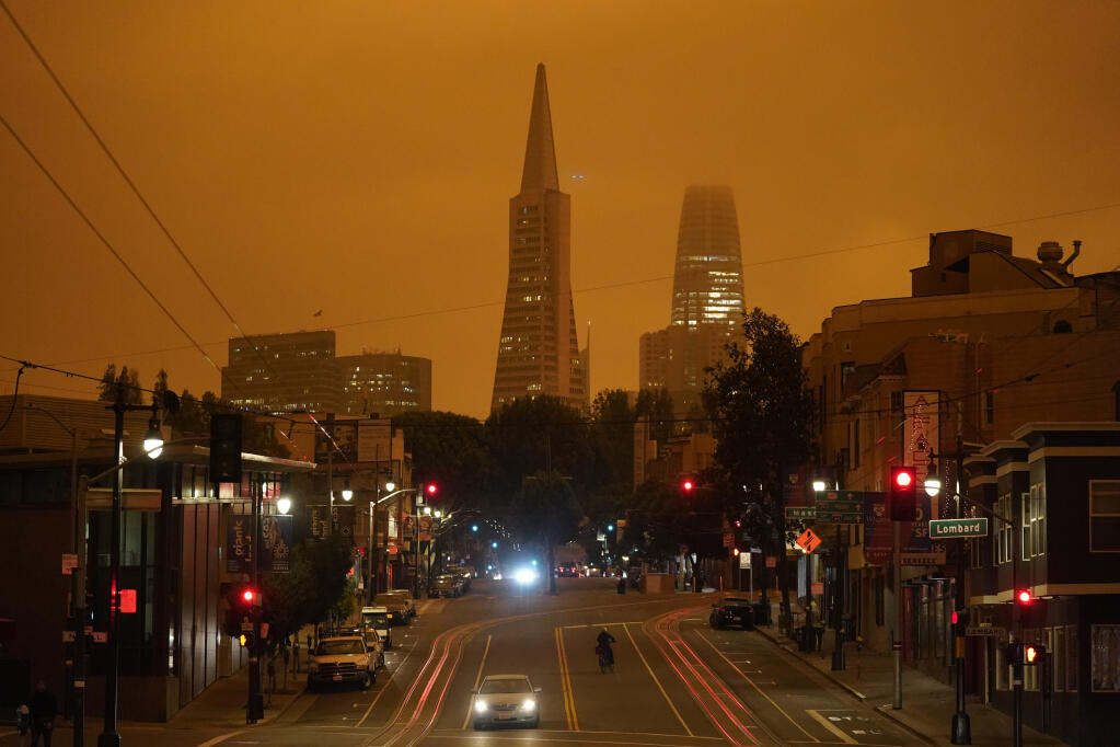 FILE - In this Sept. 9, 2020, file photo, taken at 11:42 a.m., an orange sky is seen over Columbus Ave., the Transamerica Pyramid and Salesforce Tower caused by heavy smoke from wildfires in San Francisco. Wildfires that scorched huge swaths of the West Coast churned out massive plumes of choking smoke that blanketed millions of people with hazardous pollution that spiked emergency room visits and that experts say could continue generating health problems for years. An Associated Press analysis of air quality data shows 5.2 million people in five states were hit with hazardous levels of pollution for at least a day. (AP Photo/Eric Risberg, File)