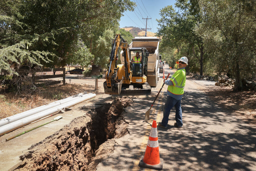 Eddie Fernandez watches for traffic as Troy Tipton digs a trench as PG&E works on placing power lines underground, along Harville Road, to help prevent customers from being impacted by Public Safety Power Shutoffs during severe weather conditions in Santa Rosa on Monday, June 28, 2021.  (Christopher Chung/ The Press Democrat)
