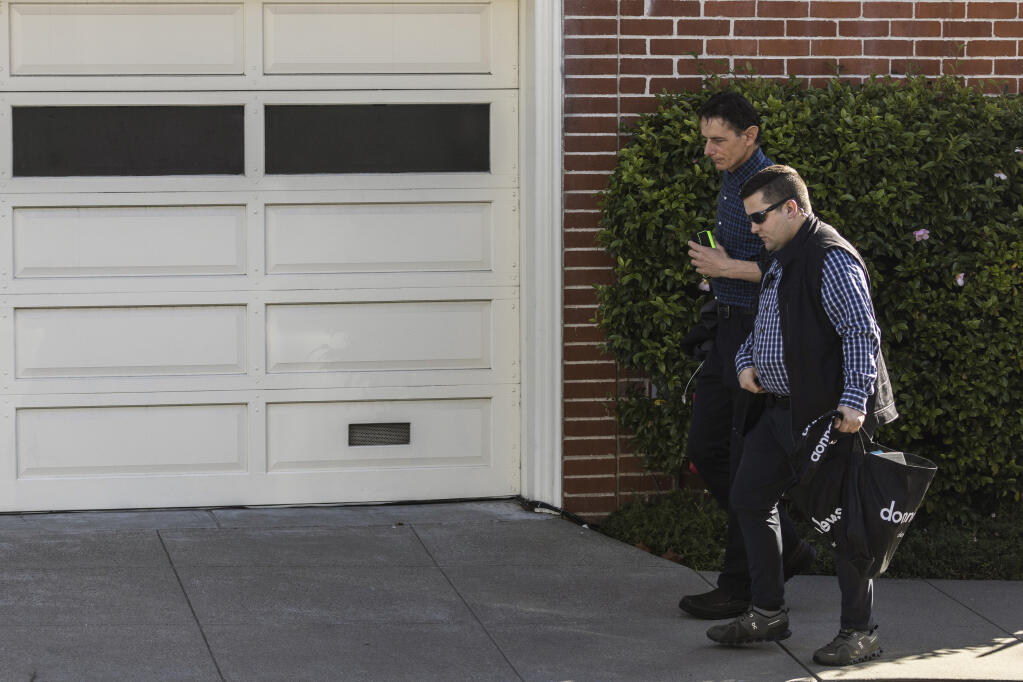 Paul Pelosi Jr., son of U.S. Speaker of the House Nancy Pelosi and Paul Pelosi, background, walks with security personnel outside his parents’ home the day after an intruder violently attacked Paul Pelosi at the home in San Francisco, Saturday, Oct. 29, 2022. (Stephen Lam/San Francisco Chronicle via AP)