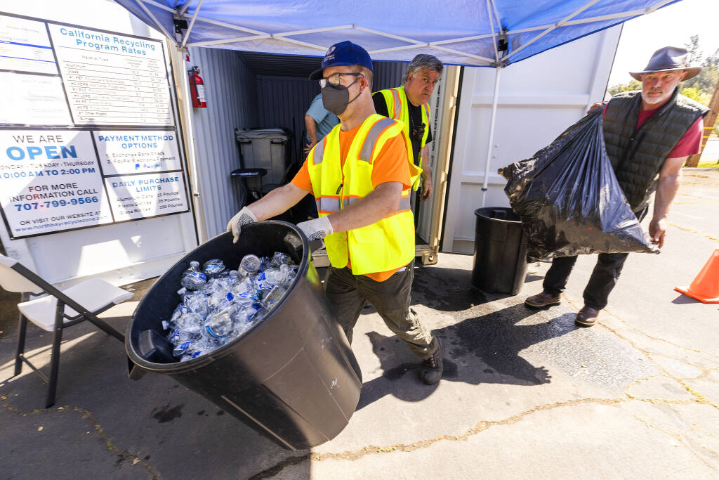 Nathan Morphew, left, hauls away a load of plastic bottles brought in March 31, 2022, by James Carrigan, right, at the new CRV beverage container recycle center at the Community Church of Sebastopol. (John Burgess / The Press Democrat)