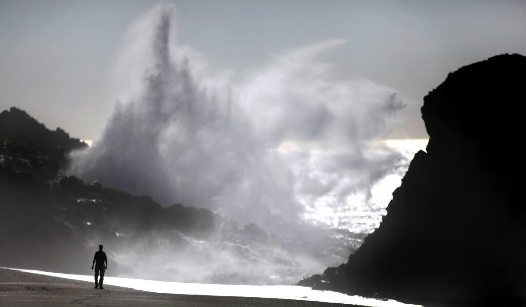 A visitor to Wright's Beach watches as a sneaker wave crashes in to Duncan's Landing, Monday, Dec. 7, 2020, north of Bodega Bay. Coastal visitors should use caution through Saturday evening, when a high surf advisory will be in place. (Kent Porter / The Press Democrat) 2020