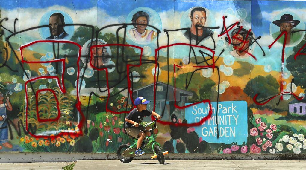 Christopher Hernandez, 6, rides his bike past a mural covered in gang graffiti at Martin Luther King Jr. Park in the South Partk neighborhood of Santa Rosa. (JOHN BURGESS/The Press Democrat)