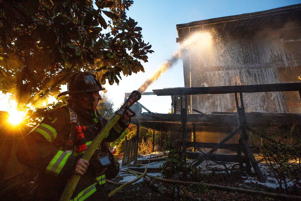 Santa Rosa fire engineer Dean Bourdage puts out hot spots after he and other firefighters extinguished a house fire on San Ramon Way in Santa Rosa, California, on Saturday, October 5, 2019. (Alvin Jornada / The Press Democrat)