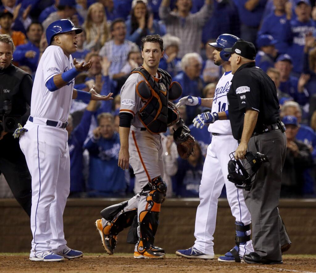 Kansas City Royals runners Salvador Perez, left, and Omar Infante talk with the umpire after scoring during the 6th inning of Game 2 of the World Series at Kauffman Stadium on Wednesday, October 22, 2014 near Kansas City, Missouri. (BETH SCHLANKER/ The Press Democrat)