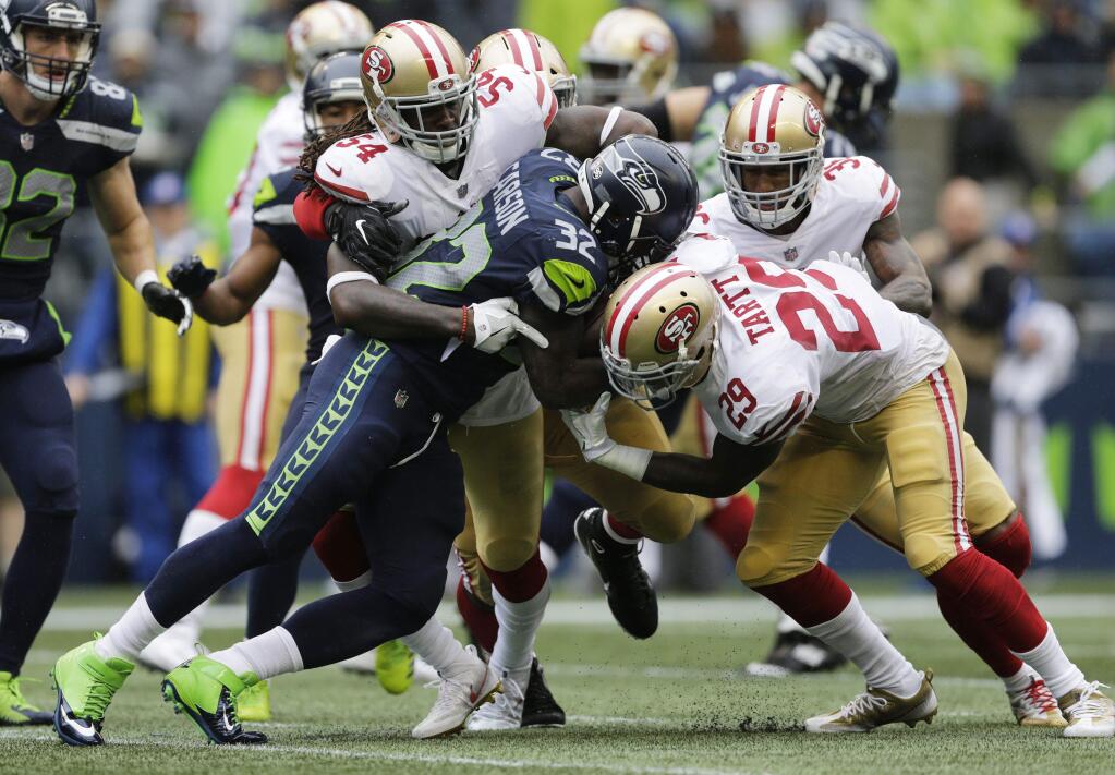 Seattle Seahawks running back Chris Carson (32) rushes against San Francisco 49ers free safety Jaquiski Tartt, right, as he is tackled by the 49ers' Ray-Ray Armstrong (54) in the second half Sunday, Sept. 17, 2017, in Seattle. (AP Photo/John Froschauer)