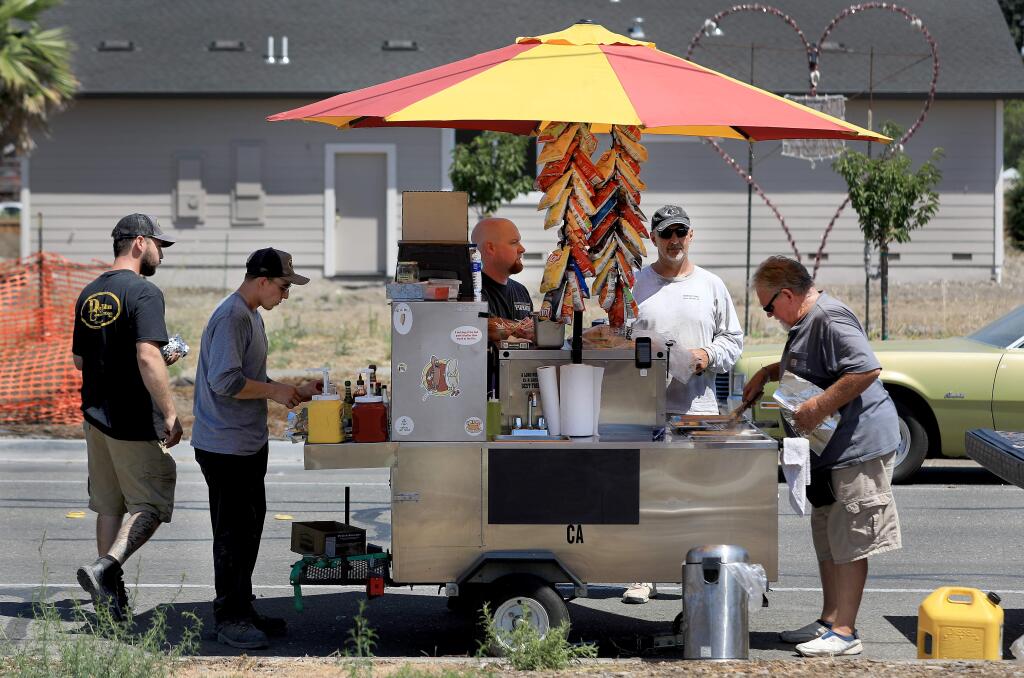 Hot dog vendor Lowell Bryan, 71, right, does a brisk business as, from left, Derek Chapman, Mitch Long, John O'Sullivan and Jim Hammond purchase their lunches in Coffey Park's rebuild zone, Thursday, July 25, 2019. (Kent Porter / The Press Democrat) 2019