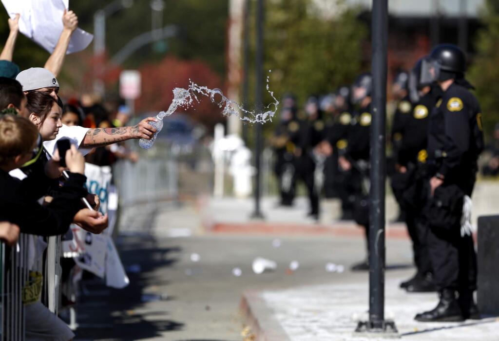 Jose Godoy tosses water towards deputies as they stand guard at the Sonoma County Sheriff's Office following a march for Andy Lopez in Santa Rosa on Tuesday, Oct. 29, 2013. (BETH SCHLANKER/ PD FILE)