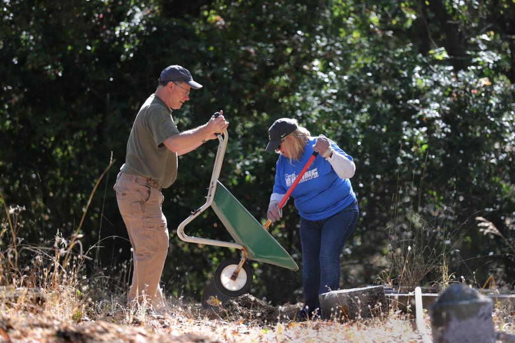 James Stettler and Ingrid Howard work to spread mulch on a pathway at the Bennett Valley Cemetery in Santa Rosa on Wednesday, September 11, 2019. (BETH SCHLANKER/ The Press Democrat)