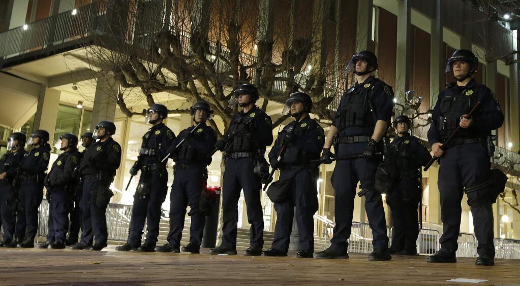 FILE - In this Feb. 1, 2017 file photo, University of California, Berkeley police officers guard the building where Breitbart News editor Milo Yiannopoulos was to speak in Berkeley, Calif. In a cost breakdown released Sunday, Feb. 4, 2018, the university said it spent almost $4 million on security during a one-month spate of free speech events last year, when the famously liberal campus became a flashpoint for country's political divisions. (AP Photo/Ben Margot, File)