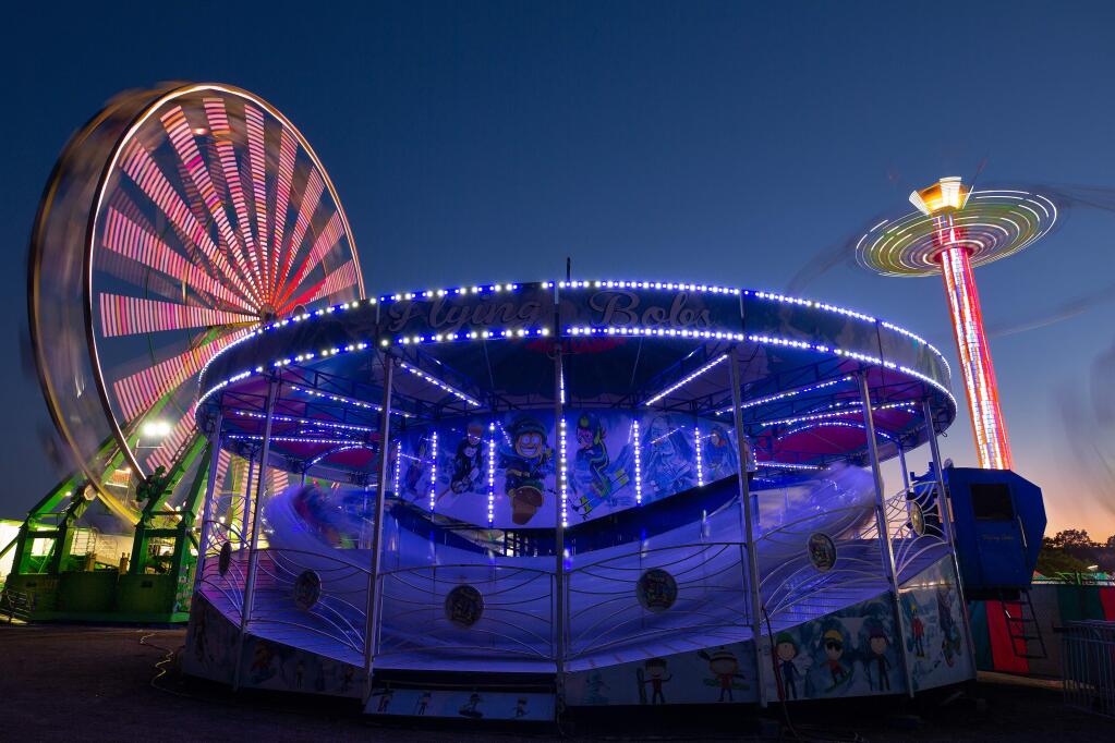 The Flying Bobs, Giant Wheel and Vertigo rides twirl around at the Sonoma County Fair on Aug. 1. (ALVIN JORNADA / The Press Democrat)