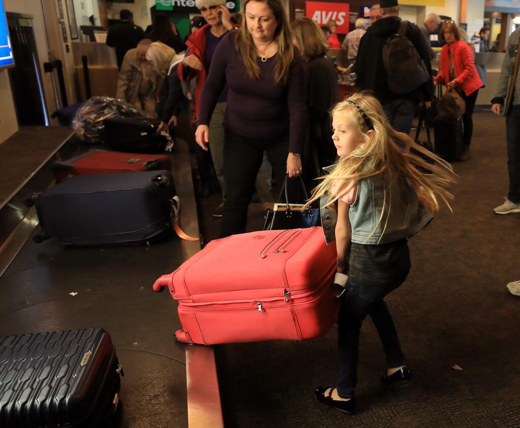 Audrey and Simone Smith of Fort Bragg gather their bags at the Charles M. Schulz Sonoma County Airport Monday, Nov. 19, 2018 after arriving from Southern California for an early holiday with family. (Kent Porter / The Press Democrat) 2018