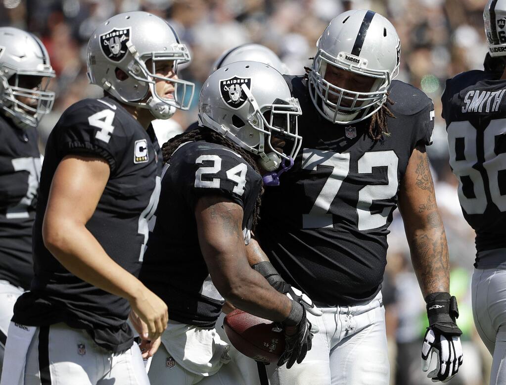 Oakland Raiders running back Marshawn Lynch (24) is congratulated by quarterback Derek Carr (4) and tackle Donald Penn (72) after scoring a touchdown against the New York Jets during the first half in Oakland, Sunday, Sept. 17, 2017. (AP Photo/Marcio Jose Sanchez)