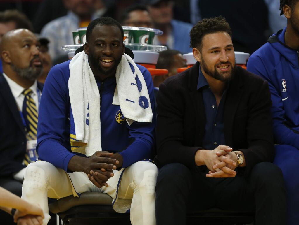 In this Wednesday, Oct. 30, 2019 photo, the Golden State Warriors' Draymond Green, left, and Klay Thompson sit on the bench in the fourth quarter against the Phoenix Suns in San Francisco. (Nhat V. Meyer/San Jose Mercury News via AP)