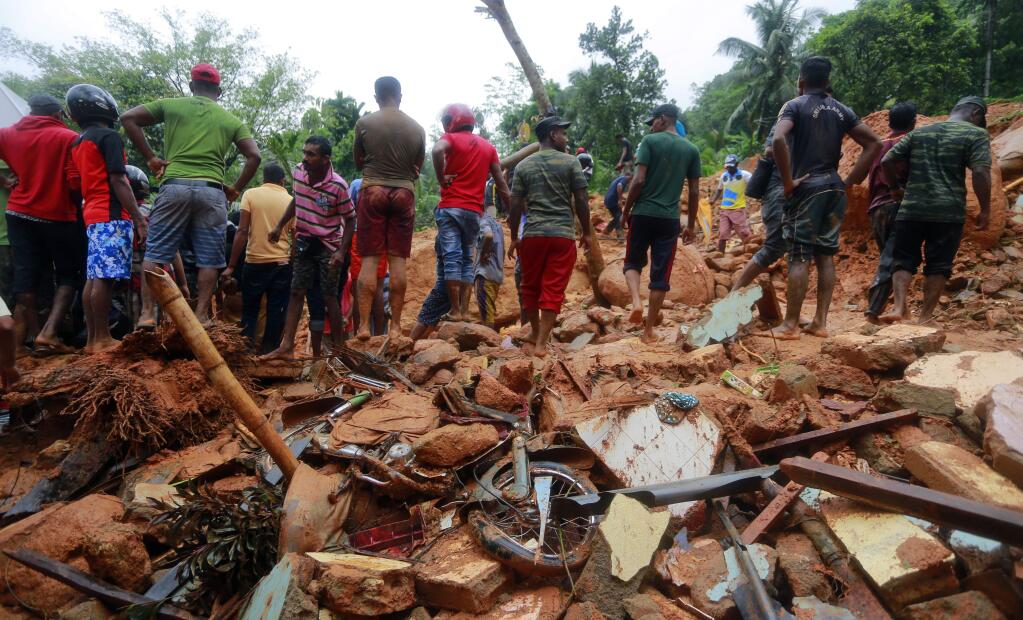 Sri Lankan military rescuers and villagers stand on the debris of a house that was destroyed in a landslide in Bellana village in Kalutara district, Sri Lanka, Friday, May 26, 2017. Mudslides and floods triggered by heavy rains in Sri Lanka killed more than a dozen people with four others missing, Home Affairs Minister Vajira Abeywardana said Friday. (AP Photo/Eranga Jayawardena)