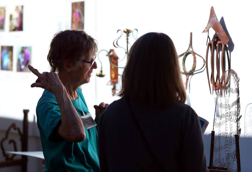 Artist Susandra Spicer, left, talks with Shay Reeves, of Colorado, about her metal art sculptures, during the Sonoma County Art Trails Open Studio Tour, in Sebastopol on Sunday, October 12, 2014. (Christopher Chung/ The Press Democrat)