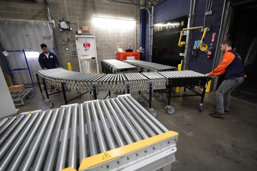 FILE- In this Nov. 9, 2018, file photo Laurence Marzo, left, and Ty Ford, right, move a conveyor belt into place to help unload a truck carrying merchandise at a Walmart Supercenter in Houston. On Friday, Dec. 7, the U.S. government issues the November jobs report. (AP Photo/David J. Phillip, File)