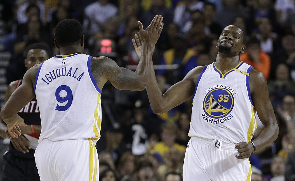 Golden State Warriors' Kevin Durant, right, is congratulated by Andre Iguodala after scoring against the Portland Trail Blazers during the first half of a preseason NBA basketball game Friday, Oct. 21, 2016, in Oakland, Calif. (AP Photo/Ben Margot)