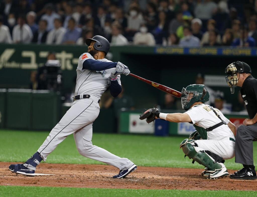 Seattle Mariners' Domingo Santana hits a grand slam off Oakland Athletics starter Mike Fiers in the third inning of Game 1 of their Major League opening series baseball game at Tokyo Dome in Tokyo, Wednesday, March 20, 2019. Athletics catcher is catcher Nick Hundley. (AP Photo/Toru Takahashi)