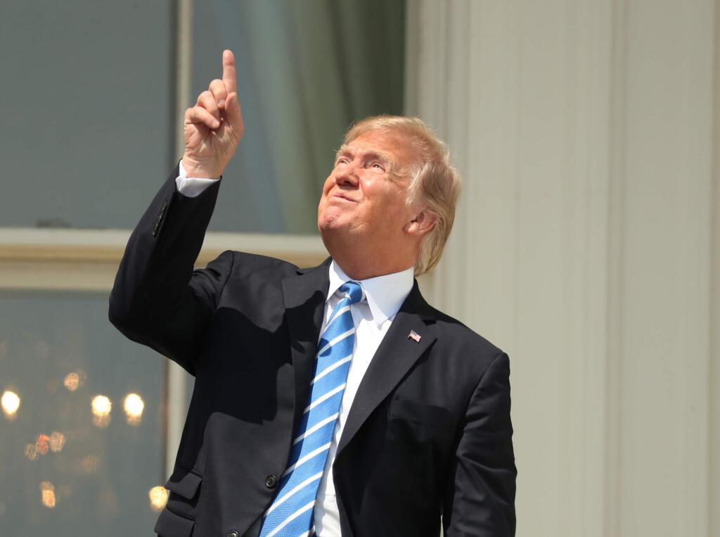 President Donald Trump points skyward before donning protective glasses to view the solar eclipse, Monday, Aug. 21, 2017, at the White House in Washington . (AP Andrew Harnik)