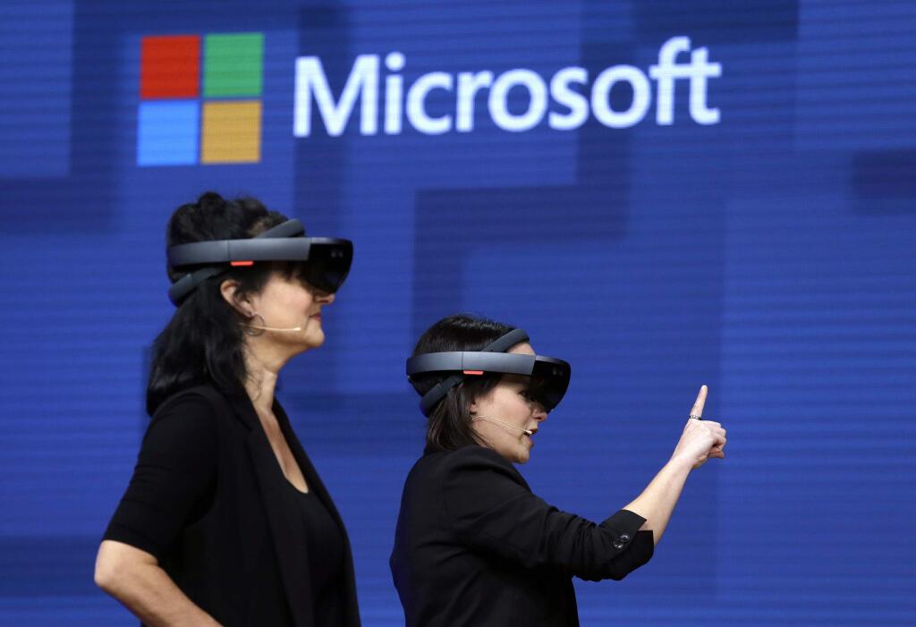 FILE- In this May 11, 2017, file photo, members of a design team at Cirque du Soleil demonstrate use of Microsoft's HoloLens device in helping to virtually design a set at the Microsoft Build 2017 developers conference in Seattle. Federal contract records show the U.S. Army has awarded Microsoft a $480 million contract to supply its HoloLens headsets to soldiers. The head-mounted displays use augmented reality, which means viewers can see virtual imagery superimposed over the real-world scenery in front of them. Microsoft says the technology will provide troops with better information to make decisions.(AP Photo/Elaine Thompson, File)