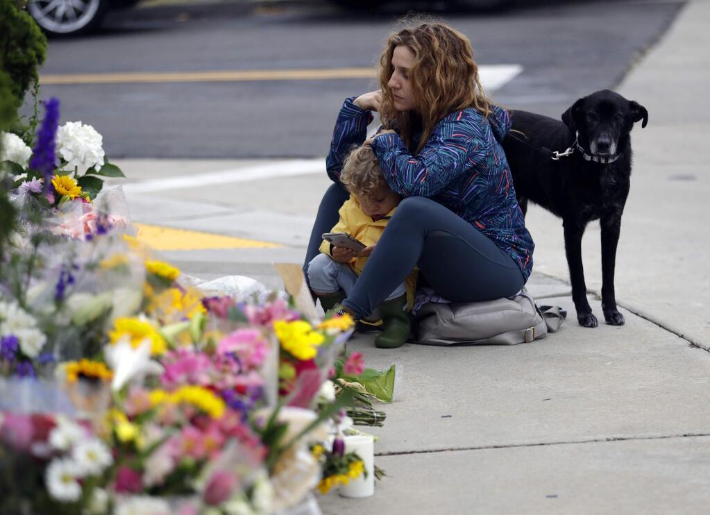 Ali De Leon pauses at a growing memorial with her son Leo and her dog Vinny across the street from the Chabad of Poway synagogue in Poway, Calif., on Monday, April 29, 2019. A gunman opened fire on Saturday, April 27 at the synagogue as dozens of people were worshipping exactly six months after a mass shooting in a Pittsburgh synagogue. (AP Photo/Greg Bull)