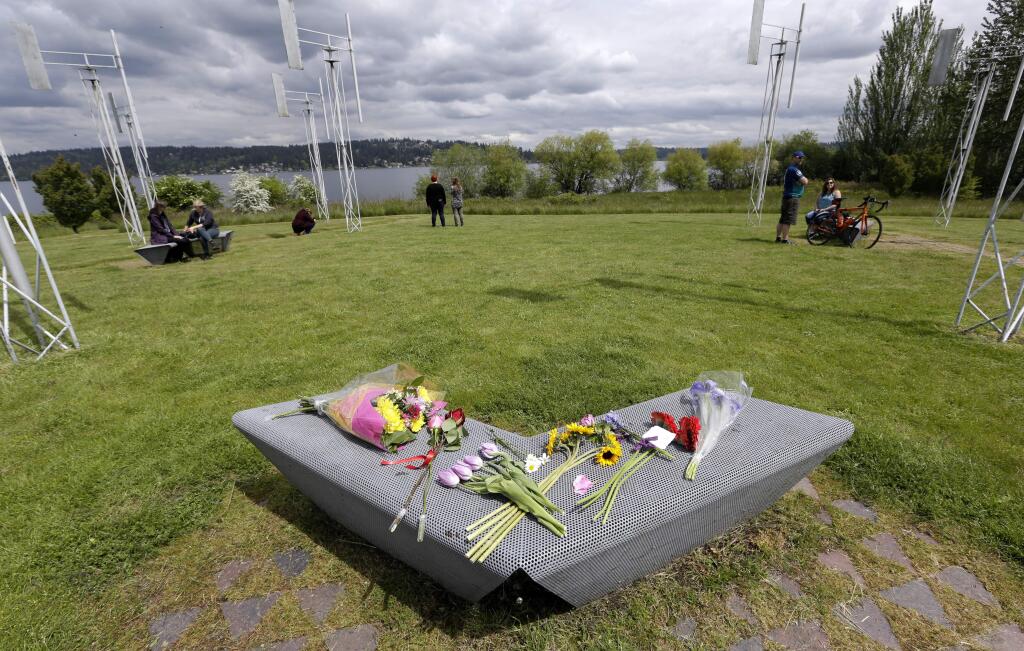 Flowers sit on a bench at the Sound Garden sculpture, for which the band Soundgarden was named, in Seattle's Magnuson Park in tribute to Chris Cornell, Thursday, May 18, 2017. The sculpture features vertical, organ-like pipes that make sounds depending upon wind direction and speed, and overlooks Lake Washington. Cornell, one of the most lauded and respected contemporary lead singers in rock music with his bands Soundgarden and Audioslave, hanged himself Wednesday in a Detroit hotel room, according to the city's medical examiner. He was 52. (AP Photo/Elaine Thompson)