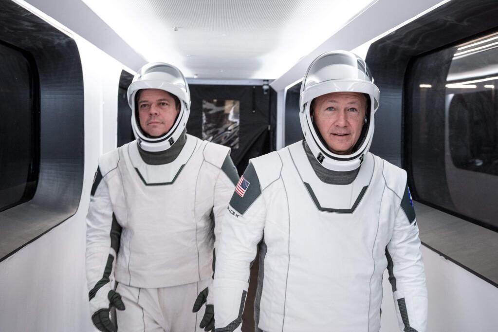 In this Jan. 17, 2020 photo made available by SpaceX, NASA astronauts Bob Behnken, left, and Doug Hurley, wearing SpaceX spacesuits, walk through the Crew Access Arm connecting the launch tower to the SpaceX Crew Dragon spacecraft during a dress rehearsal at NASA's Kennedy Space Center in Cape Canaveral, Fla. For their May 27, 2020 mission, Hurley will be in charge of launch and landing and Behnken will oversee rendezvous and docking at the International Space Station. (SpaceX via AP)