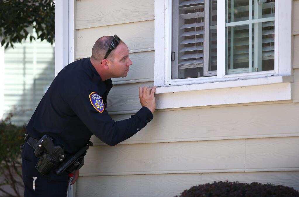 Santa Rosa Police Officer Nick Vercelli looks for activity in a residence of a registered gang member on parole, as part of the department's gang unit, in Santa Rosa on Thursday, August 21, 2014. (Christopher Chung/ The Press Democrat)
